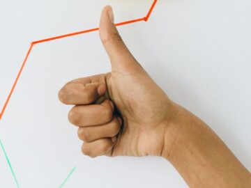 A hand giving a thumbs up in front of a profit growth chart, highlighting success.