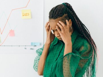 Businesswoman in distress over financial graph showing loss indoors.