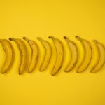 Top view of tasty ripe bananas with blots on peel composed in row on yellow background