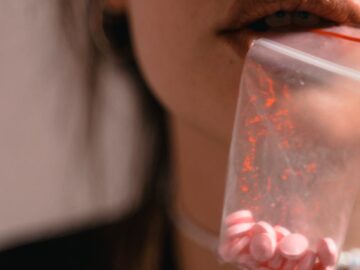A close-up of a person holding a bag of pills, exploring themes of substance use and healthcare.