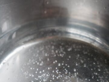 Boiling water in a stainless steel pot with visible bubbles, perfect for culinary themes.