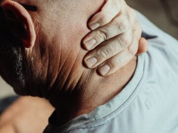 Man with neck pain holding his neck in discomfort, conveying tension or stress.