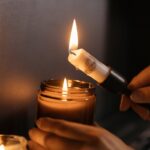 Close-up of hands lighting a candle, creating a warm and cozy ambiance indoors.