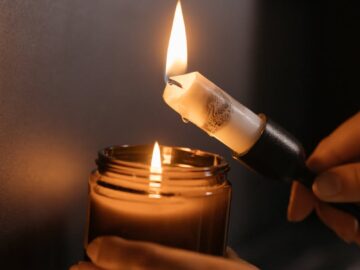 Close-up of hands lighting a candle, creating a warm and cozy ambiance indoors.