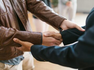 Two business professionals shaking hands, symbolizing teamwork and collaboration indoors.