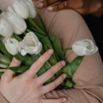 Close-up of diverse hands holding a bouquet of white tulips in a warm embrace.