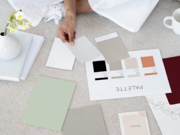 Designer sits on carpet with color palettes and samples, planning creative project.