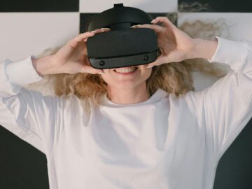 Woman lying down smiling with VR headset, embracing virtual reality indoors.