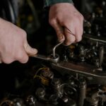 Close-up of a mechanic using a wrench and Allen key to fix an engine.