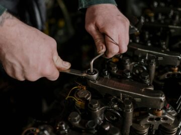 Close-up of a mechanic using a wrench and Allen key to fix an engine.