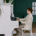A young boy plays a piano indoors, honing his musical skills in a warm, cozy room.