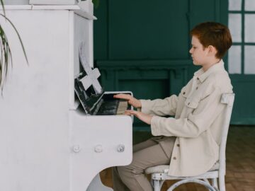 A young boy plays a piano indoors, honing his musical skills in a warm, cozy room.