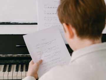 A child focused on reading sheet music at a piano, emphasizing musical learning.