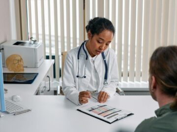 A doctor consulting with a patient in an office, discussing a medical chart.