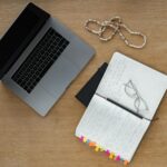 A neat desk setup with laptop, notebook, and glasses on a wooden surface, perfect for studying or working from home.