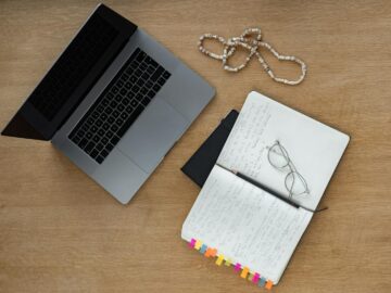 A neat desk setup with laptop, notebook, and glasses on a wooden surface, perfect for studying or working from home.