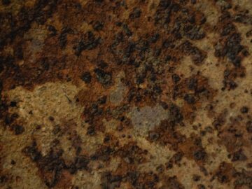 Detailed close-up of a rusty corroded metal surface showing gritty texture and brown tones.