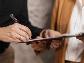 Close-up of two professionals signing a business document, emphasizing collaboration and negotiation.