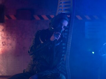 A person in a futuristic setting with an oxygen mask and dramatic neon lighting.