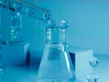 Laboratory experiment showcasing a beaker with bubbling liquid and pipette against a blue backdrop.