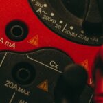 Detailed image of a red multimeter, showcasing measurement dial and connectors, ideal for tech enthusiasts.
