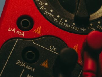 Detailed image of a red multimeter, showcasing measurement dial and connectors, ideal for tech enthusiasts.
