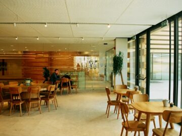 A bright and spacious cafeteria with wooden furniture and large glass windows.