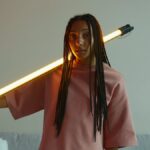 Creative portrait of a young woman holding a glowing LED light in a modern setting.