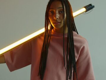Creative portrait of a young woman holding a glowing LED light in a modern setting.