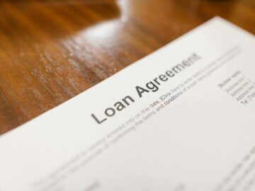 Detailed loan agreement document close-up on a wooden table representing legal and financial concepts.