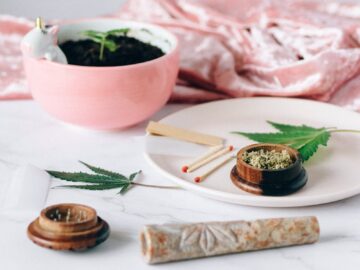 Marble surface with cannabis leaves, grinder, and pink planter creating a relaxed atmosphere.