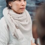 A woman in a light scarf participates in an interview indoors, captured during the day.