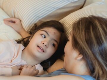 Heartwarming moment between a mother and daughter with Down syndrome enjoying a tender bond in the bedroom.
