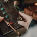 Hands holding a decorative journal and wand, evoking a magical and mystical theme.