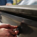 Close-up of hands unlocking a car trunk with a key, focusing on detail.