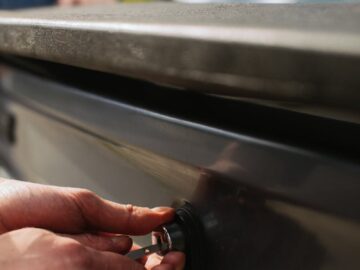 Close-up of hands unlocking a car trunk with a key, focusing on detail.