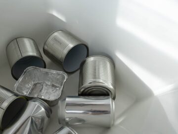Empty aluminum cans collected in a white recycling bin highlight the importance of sustainable living.