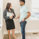 Real estate agent and client in business attire discussing a contract indoors.