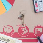 Flat lay of calculator, keys, house paperwork for relocation planning.