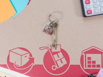 Flat lay of calculator, keys, house paperwork for relocation planning.