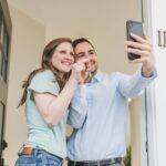 Happy couple takes a selfie while celebrating keys to their new home.
