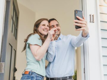 Happy couple takes a selfie while celebrating keys to their new home.