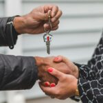 Close-up of a realtor handing over a house key to a new homeowner, symbolizing ownership and investment.