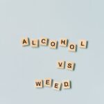 Scrabble tiles spelling 'Alcohol vs Weed' on a light blue background.