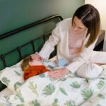A woman attending to a child lying in bed, showcasing care and concern.