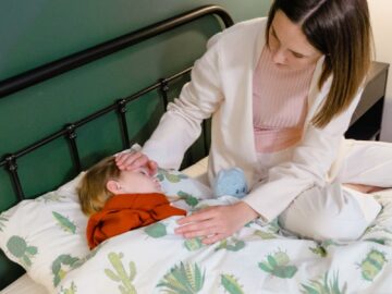 A woman attending to a child lying in bed, showcasing care and concern.