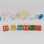 Colorful blocks spelling 'autism' with blurred toys in background.