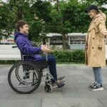 A joyful couple in a park, featuring a man in a wheelchair and a woman in a coat, sharing a moment.