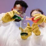 Two scientists mixing colorful liquids in a laboratory setting, showcasing teamwork and scientific research.