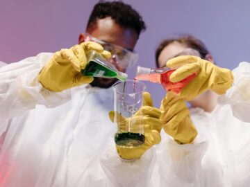 Two scientists mixing colorful liquids in a laboratory setting, showcasing teamwork and scientific research.